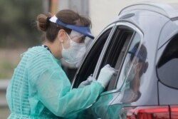 A paramedic of the Italian Red Cross takes a swab to test for Covid-19 from a motorist at a drive-through COVID-19 testing center at a parking area of Rome's Leonardo da Vinci international airport in Fiumicino, Sept. 2, 2020.
