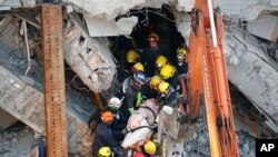 救援人员2月7日从台南大地震倒塌的建筑中搬运出一具尸体。