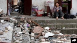 2013年4月21日四川省芦山县古城村的一名妇女望着她的被地震摧毁的房屋。