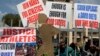 Athletes holds banners and look through the locked the gate at the Kenya Athletic offices in Nairobi, Kenya, Monday, Nov. 23, 2015. The International Association of Athletics Federations (IAAF) announced in November it has been investigating Kenya since March for allegations of covering up doping