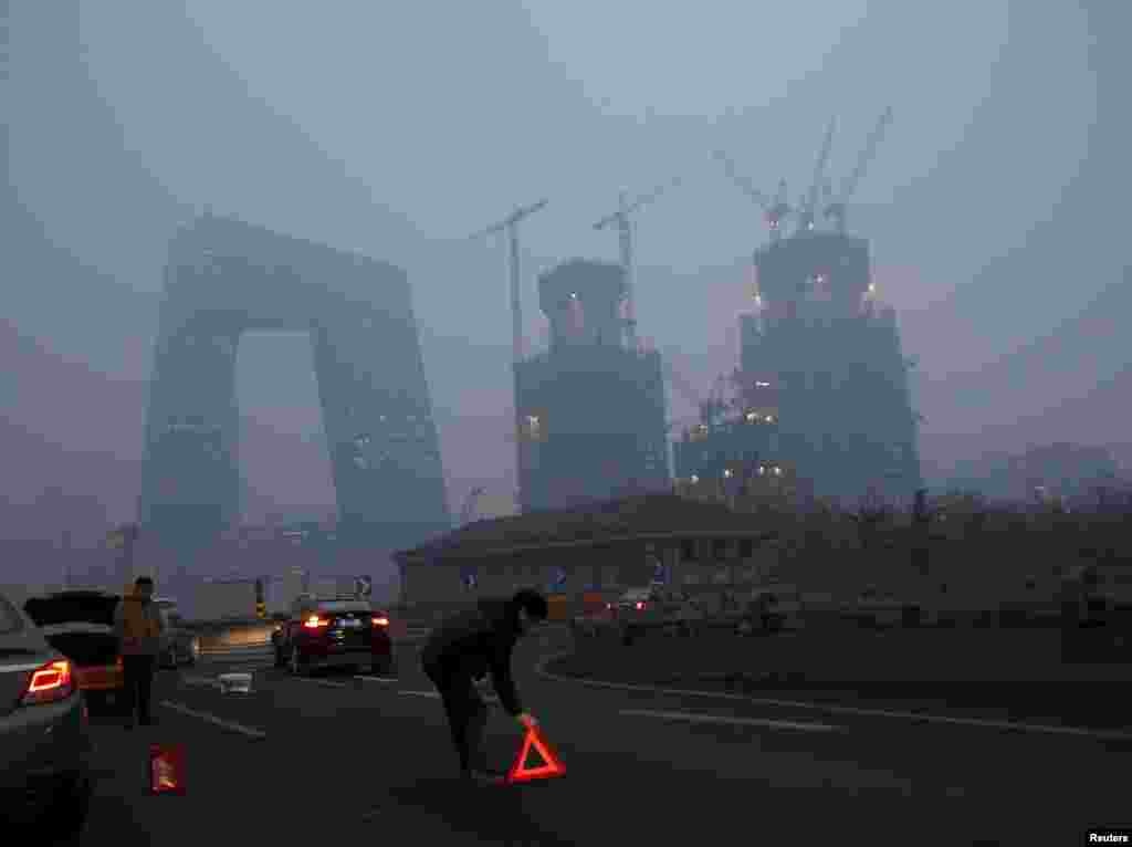 2015年12月8日，在北京首次发布空气污染红色警报后， 在雾霾中有车辆出事，有人放置橙色标志