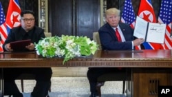Le président des États-Unis, Donald Trump, tient le document que lui et le dirigeant nord-coréen Kim Jong Un ont signé à Capella, sur l'île de Sentosa, le 12 juin 2018, à Singapour (AP Photo / Evan Vucci)