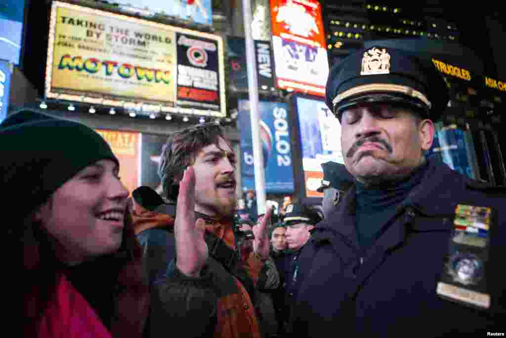 A NYPD policeman (R) reacts next to people protesting against the Staten Island death of Eric Garner during an arrest in July, int midtown Manhattan in New York, Dec. 3, 2014.