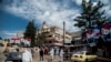 FILE - In this March 24, 2020, file photo, workers spray disinfectant to prevent the spread of the coronavirus on a street lined with billboards showing Syrian President Bashar Assad, in Qamishli, Syria.