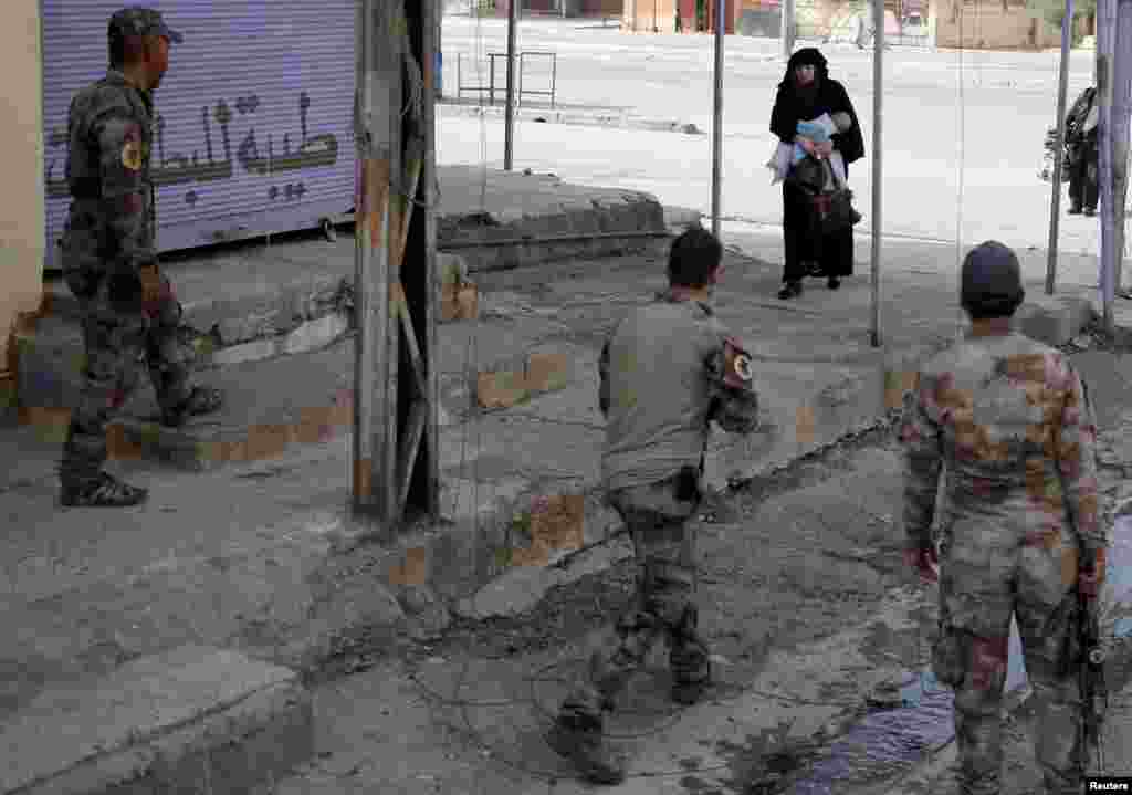 ស្រ្តី​ម្នាក់​ឱប​កូន​ ខណៈ​ពេល​ធ្វើ​ដំណើរ​ឆ្លងកាត់​ពី​ផ្នែក​នៃ​ក្រុង Mosul ដែល​គ្រប់គ្រង​ដោយ​ពួក​សកម្មប្រយុទ្ធ​រដ្ឋឥស្លាម​ចូល​ទៅ​ក្នុង​តំបន់​មួយ​ទៀត​នៃ​ក្រុង​នេះ​ ដែល​គ្រប់គ្រង​ដោយ​កងទាហាន​ពិសេស​អ៊ីរ៉ាក់។