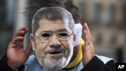 A man covers his face with a mask of Egypt President Mohamed Morsi during a protest in front of the chancellery against the visit of Morsi prior to a meeting of him with German Chancellor Angela Merkel in Berlin, Germany, January 30, 2013.