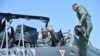 The 27th Chief of Army Staff of the Indian Army Bipin Rawat (L) waves after sitting in the co-pilot seat of a Light Combat Aircraft of the Indian Airforce during the Aero India airshow at the Yelahanka Air Force station, in Bangalore on Feb. 21, 2019.
