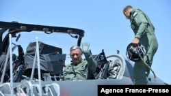 The 27th Chief of Army Staff of the Indian Army Bipin Rawat (L) waves after sitting in the co-pilot seat of a Light Combat Aircraft of the Indian Airforce during the Aero India airshow at the Yelahanka Air Force station, in Bangalore on Feb. 21, 2019.