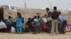 Families wait by the fence as soldiers screen incoming refugees in Khazir Camp in the Kurdish region of northern Iraq, Oct. 28, 2016. 