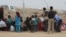 Families wait by the fence as soldiers screen incoming refugees in Khazir Camp in the Kurdish region of northern Iraq, Oct. 28, 2016. 