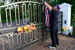 John Hensel attaches an American flag to the gate of the home of his friend and talk radio host Rush Limbaugh, in Palm Beach, Fla., Feb. 17, 2021.