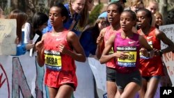 FILE - Buzunesh Deba, left, of Ethiopia, runs in a group of elite female participants past Wellesley College during the 118th Boston Marathon in Wellesley, Mass., April 21, 2014.