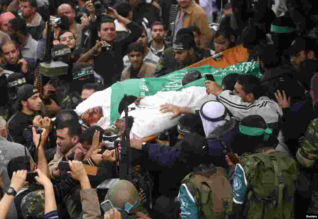 Anggota kelompok militan Hamas membawa jenazah para kamerad, yang menurut pihak medis tewas dalam serangan udara Israel, pada pemakaman di pusat Jalur Gaza (22/11).