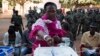 A woman casts her ballot at a polling station as soldiers watch in Bissau, April 13, 2014. 