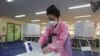 A woman wearing a face mask to help protect against the spread of the new coronavirus casts a vote for the parliamentary elections at a polling station in Seoul, South Korea, Wednesday, April 15, 2020. South Korean voters wore masks and moved slowly…