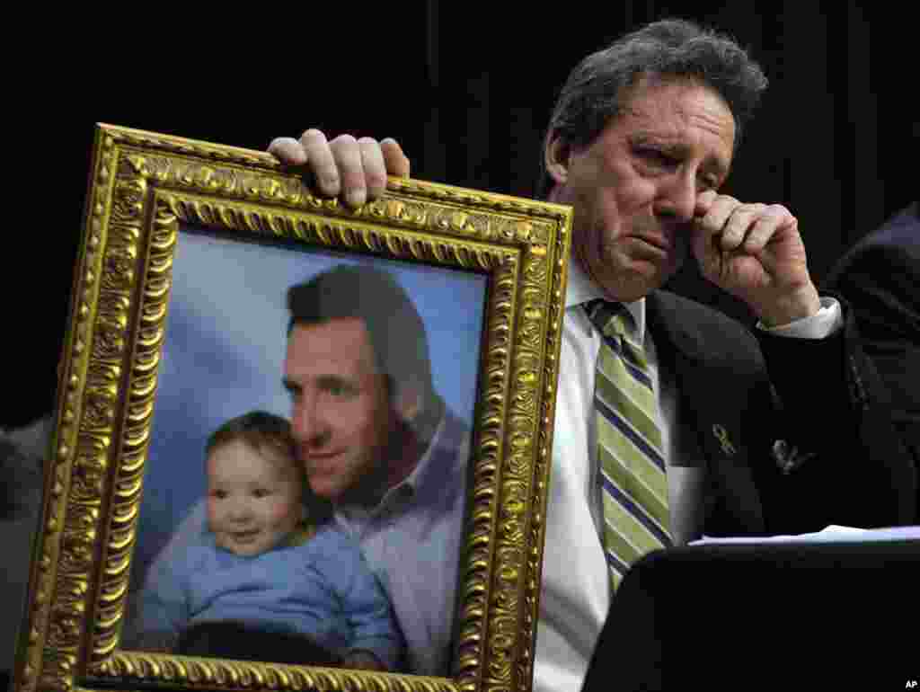 Neil Heslin, ayah Jesse, korban penembakan di SD Sandy Hook di Newtown, Connecticut, 14 Desember 2012, memegang fotonya bersama almarhum anaknya saat memberikan keterangan di Capitol Hill in Washington, D.C., di hadapan Komite Kehakiman Senat terkait pembatasan kekerasan dengan penggunaan senjata tahun 2013.