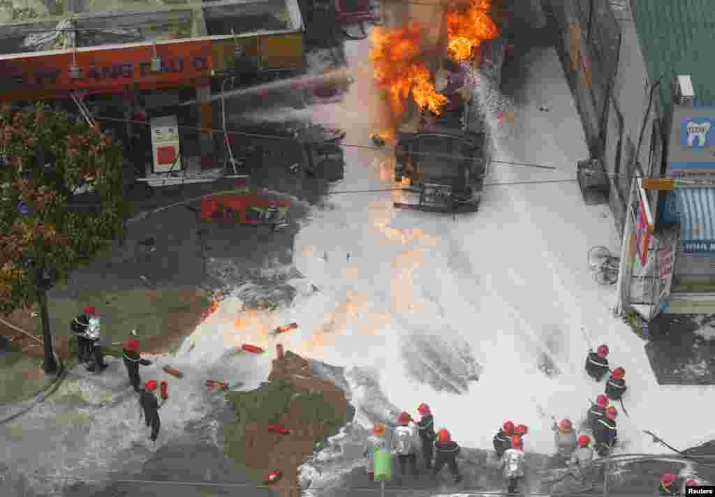 Petugas pemadam kebakaran mencoba untuk memadamkan tangki bensin yang terbakar di sebuah pom bensin di Hanoi, Vietnam.