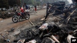 埃及人骑摩托路过开罗大学附近的纳达广场，地上是被烧毁的穆尔西画像。