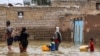 FILE - An Iranian family walks through a flooded street in a village around the city of Ahvaz, in Iran's Khuzestan province, March 31, 2019.