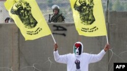 یک معترض فلسطینی در رام الله پرچم هایی دارد که عکس «مروان برغوثی» زندانی محکوم به ابد روی آن چاپ شده است. 