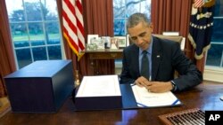 Le président américain Barack Obama signant la loi sur le budget dans le Bureau Oval de la Maison Blanche, le 18 décembre 2015 à Washington. (AP Photo/Carolyn Kaster) 