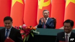 ປະ​ທານ​ປະ​ເທດ ຫວຽດ​ນາມ ທ່ານ ໂຕ ລຳ, ກາງ, ຕົບ​ມື​ຊົມ​ເຊີຍ​ໃນ​ລະ​ຫວ່າງ​ພິ​ທີ​ເຊັນ​ສັນ​ຍາ​ຢູ່​ຫໍ​ປະ​ຊຸມ​ໃຫຍ່​ຂອງ​ປະ​ຊາ​ຊົນ​ໃນ ປັກ​ກິ່ງ, 19 ສິງ​ຫາ 2024. (Andres Martinez Casares/Pool Photo via AP)