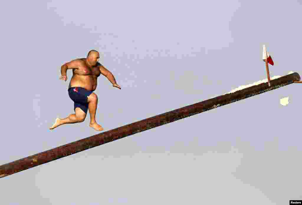 Seorang pria lari di atas &quot;gostra&quot;, sebuah tiang yang dilumuri oli, dalam pesta keagamaan St Julian, pelindung kota St. Julian&#39;s, di luar Valletta, Malta, 25 Agustus 2013. 