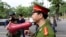 FILE - A Vietnamese police officer uses a speaker to order pedestrians including journalists to leave a closed area near the Chinese Embassy in Hanoi, Vietnam. 