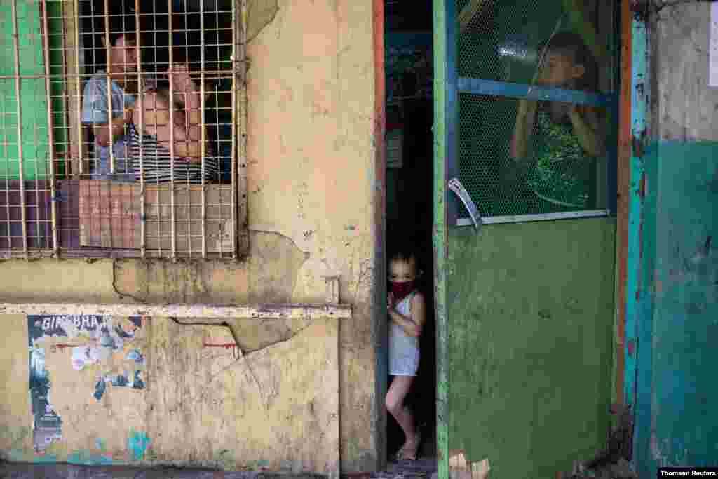필리핀 마닐라에 코로나바이러스 감염 방지를 위해 엄격한 통제령이 내려진 가운데 마스크를 슨 아이가 집 밖을 내다보고 있다.