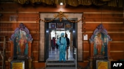 一名工作人员在孟买的一个印度教寺庙进行消毒，以避人们感染新冠病毒。图片：2020年11月15日