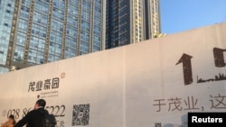 一名男子骑自行车经过四川成都的一处建筑工地 (资料照)