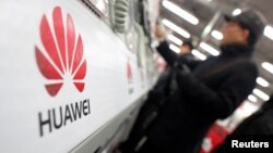 A man looks at a Huawei mobile phone as he shops at an electronic market in Shanghai, Jan. 22, 2013.