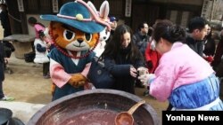 동지 절기를 이틀 앞둔 지난 20일 경기 용인시 한국민속촌에서 관람객들에게 팥죽을 나눠주고 있다. 