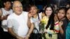 A prominent leader of Cambodia's land rights activist Tep Vanny, third from right, holds flowers as she celebrates upon the arrival at her home in Boeung Kak, in Phnom Penh, Cambodia, Aug. 20, 2018.