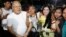 A prominent leader of Cambodia's land rights activist Tep Vanny, third from right, holds flowers as she celebrates upon the arrival at her home in Boeung Kak, in Phnom Penh, Cambodia, Aug. 20, 2018.