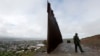 FILE - A Border Patrol agent walks near where the border wall ends that separates Tijuana, Mexico, left, from San Diego, right, Feb. 5, 2019.
