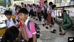 Thai teachers check the mouth of the students for hand, foot and mouth disease, before they get inside the school in Bangkok, July 25, 2012. 