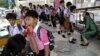 Thai teachers check the mouth of the students for hand, foot and mouth disease, before they get inside the school in Bangkok, July 25, 2012. 