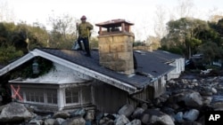 一名消防队员站在加州蒙地西托一处被泥石流掩盖的房屋顶上。（2018年1月10日）
