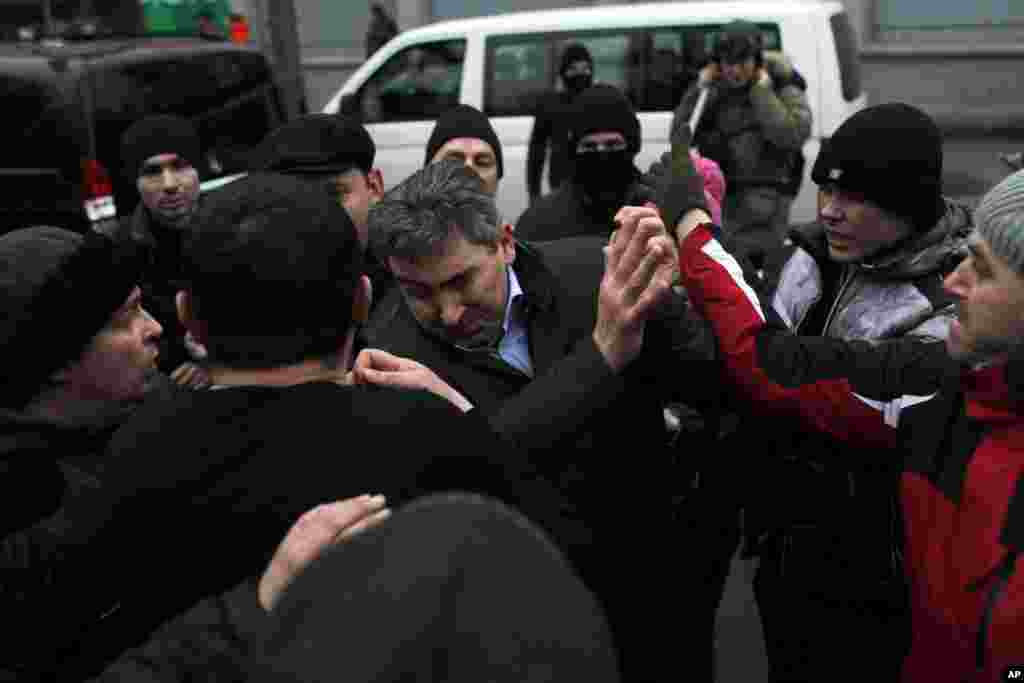 Seseorang yang diduga pendukung Presiden Viktor Yanukovych, tengah, diserang para demonstran anti-pemerintah di Kyiv.