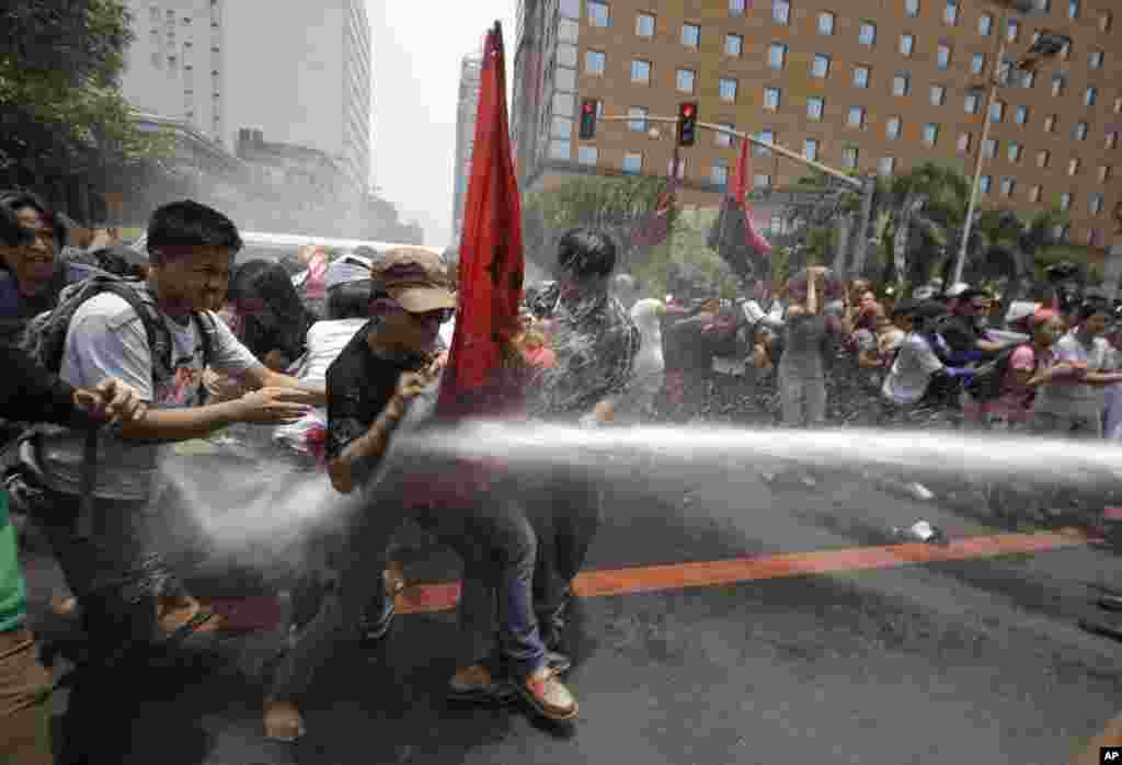 Polisi Filipina menyemprotkan air ke arah para demonstran yang berusaha mendekati komplek Kedutaan AS di Manila, Filipina untuk memprotes rencana kunjungan Presiden Obama.&nbsp;