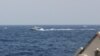 In this image provided by the U.S. Navy, an Iranian Islamic Revolutionary Guard Corps Navy fast in-shore attack craft is shown near U.S. naval vessels transiting the Strait of Hormuz, May 10, 2021. 
