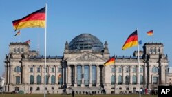 德国国会大厦，大厦前和大厦上飘扬着德国国旗。