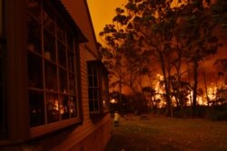 Firefighting crews from the Rural Fire Service, NSW Fire and Rescue and National Parks and Wildlife Service officers fight a bushfire encroaching on properties near Lake Tabourie, Australia, Dec. 5, 2019.