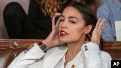 Rep. Alexandria Ocasio-Cortez, D-N.Y., holds a hair clip between her teeth as she pulls her hair back, on the opening day of the 116th Congress, at the Capitol in Washington, Thursday, Jan. 3, 2019. (AP Photo/J. Scott Applewhite)