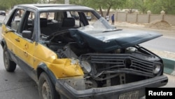 A car damaged by a bomb blast is seen in front of police headquarters in Nigeria's northeastern city of Maiduguri June 8, 2012.