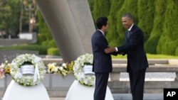 Le président américain Barack Obama serre la main du Premier ministre japonais Shinzo Abe devant le cénotaphe du Parc du mémorial de la Paix à Hiroshima, au Japon, vendredi 27 mai 2016