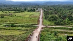 Para pengendara melintas di jalan dekat Kawasan Industri Weda Bay Indonesia di Kulo Jaya, Halmahera Tengah, Maluku Utara, 7 Juni 2024. Di kawasan itu sedang dibangun smelter nikel untuk pengembangan industri hilir. (Foto: Achmad Ibrahim/AP Photo)