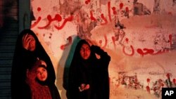 A Bahraini woman and children pray in a street in Malkiya, Bahrain, after participating in call of "God is greater" that echoed through opposition villages nationwide, Aug. 12, 2013. 