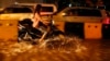 A Cambodian motorist rides a scooter through a street flooded by heavy rain fall in Phnom Penh, Cambodia, Friday, July 31, 2015. (AP Photo/Heng Sinith)